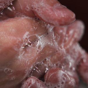 Close-up of hands with soap bubbles against a dark background